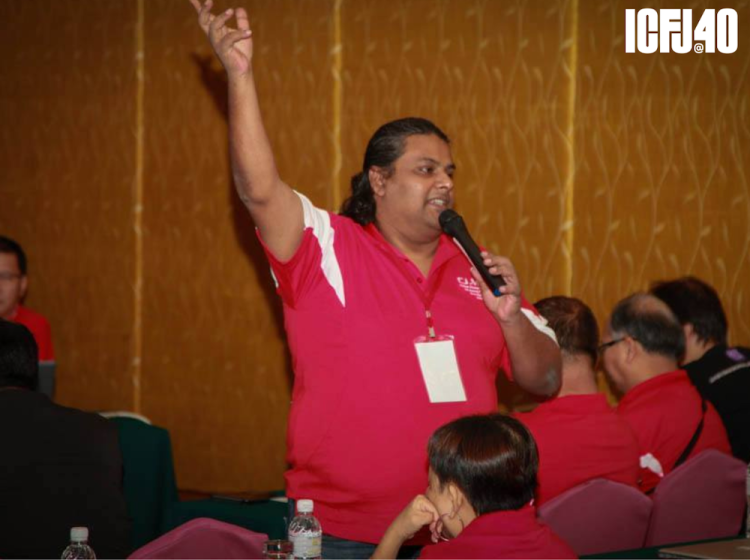 A photograph of Maran Perianen holding a microphone.