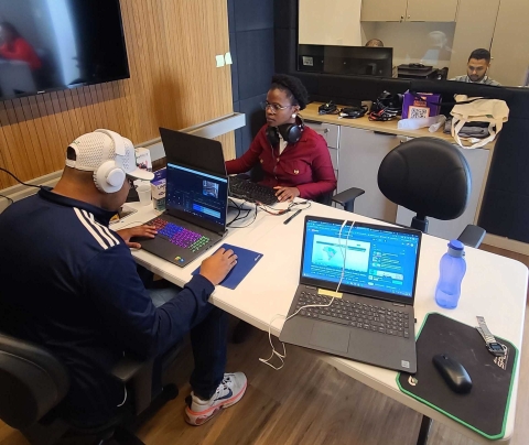 A man and woman sitting across from each other working on computers at the Alma Preta newsroom in Sao Paulo, Brazil.