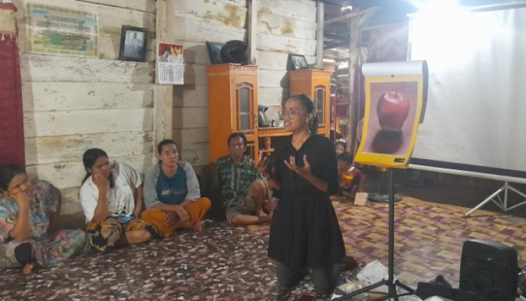 A photo of Zulfa Amira Zaed presenting to a room of people sitting on rugs.